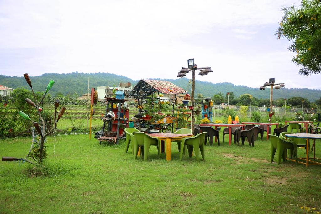 a group of tables and chairs in a field at Corbett Treat Resort in Rāmnagar