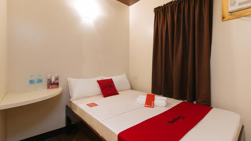 Habitación pequeña con cama con almohadas rojas. en RedDoorz near EDSA Camp Crame en Manila
