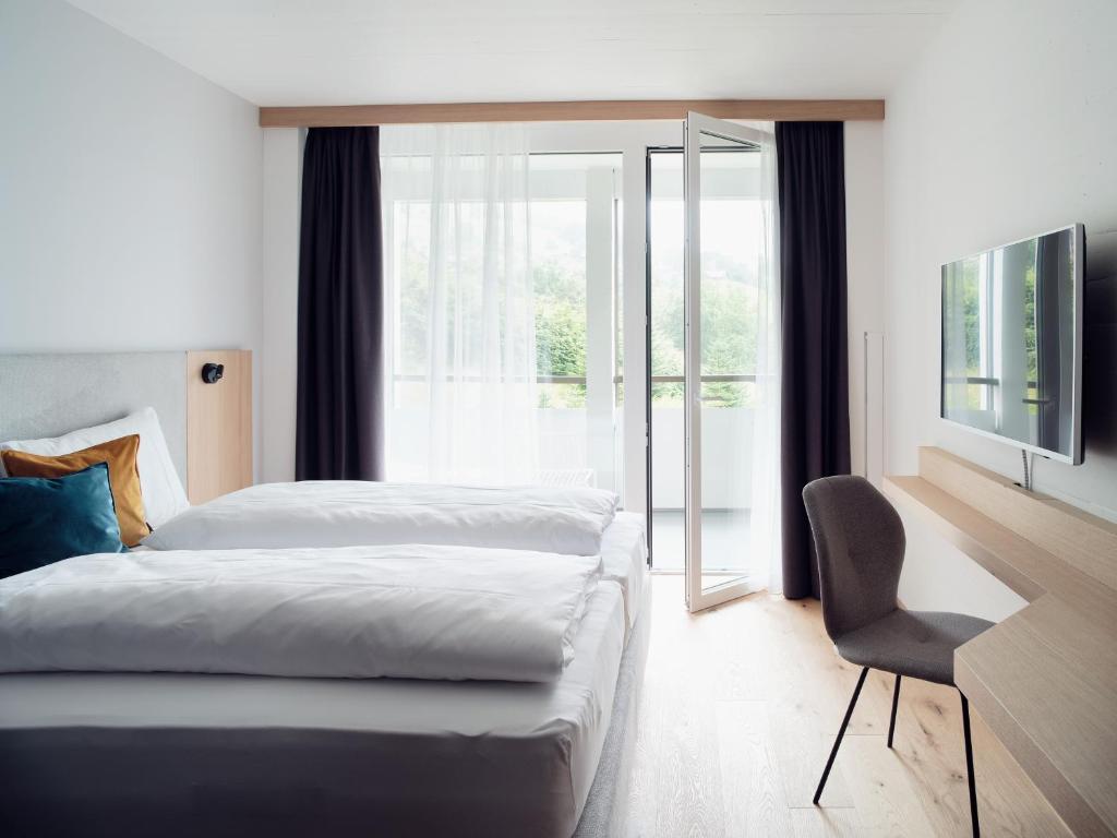 ein Schlafzimmer mit einem Bett, einem Stuhl und einem Fenster in der Unterkunft Hotel Neu-Schönstatt in Quarten