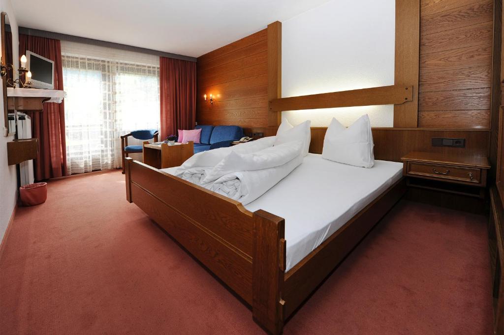 1 dormitorio con 1 cama grande con sábanas blancas en Frühstückspension Haus Kreuzmayr en Gaschurn