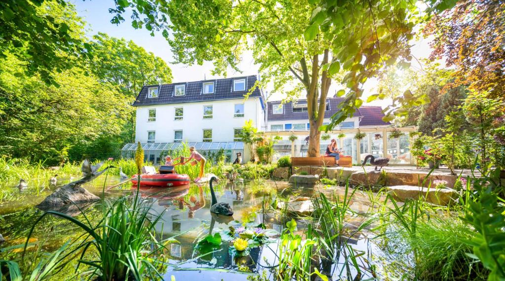 un jardín frente a una casa blanca con un estanque en Gartenhotel Fettehenne, en Erkrath