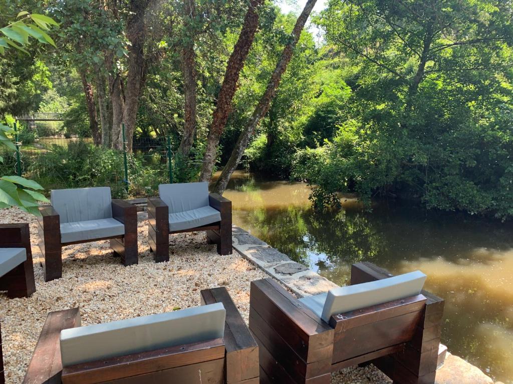 a couple of chairs sitting next to a river at Villa au bord de la Rivière avec Jacuzzi in Ségur-le-Château