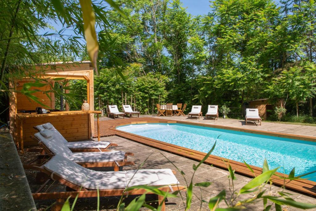 una piscina con sillas y una mesa en Chambre d'Hôtes Au Jardin Des Saveurs, en Cordes-sur-Ciel