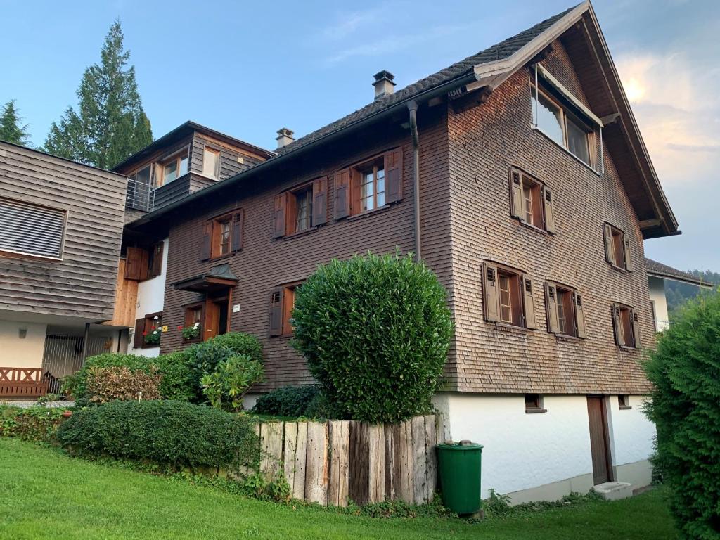 ein großes Backsteinhaus mit einem Zaun davor in der Unterkunft Bauernhaus am Pfänderhang mit Seeblick in Lochau