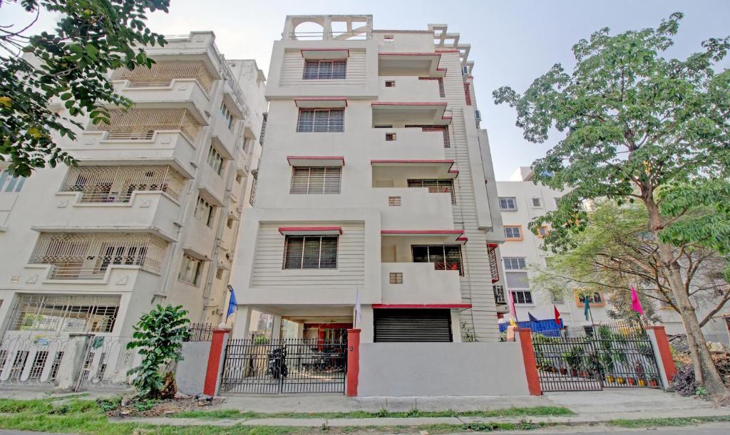 un edificio blanco alto con una valla delante en FabHotel Ashraya Inn, en Calcuta