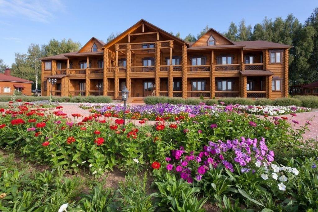 una gran casa de madera con flores delante en Hotel Semigorie, en Shaldovo