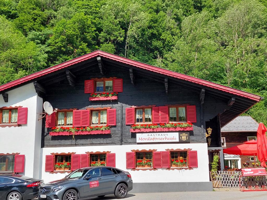 a black and white building with red shutters at Gasthaus Pension Montafonerhüsli in Sankt Gallenkirch