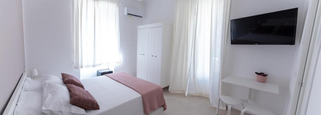 a white bedroom with a bed and a television at Casa Thuja in Syracuse