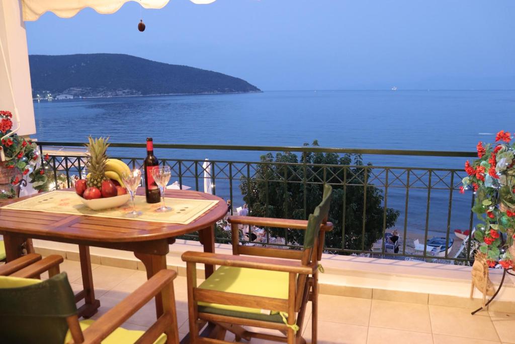 uma varanda com uma mesa com frutas e vista para o oceano em Sea and Sun apartment em Nea Peramos