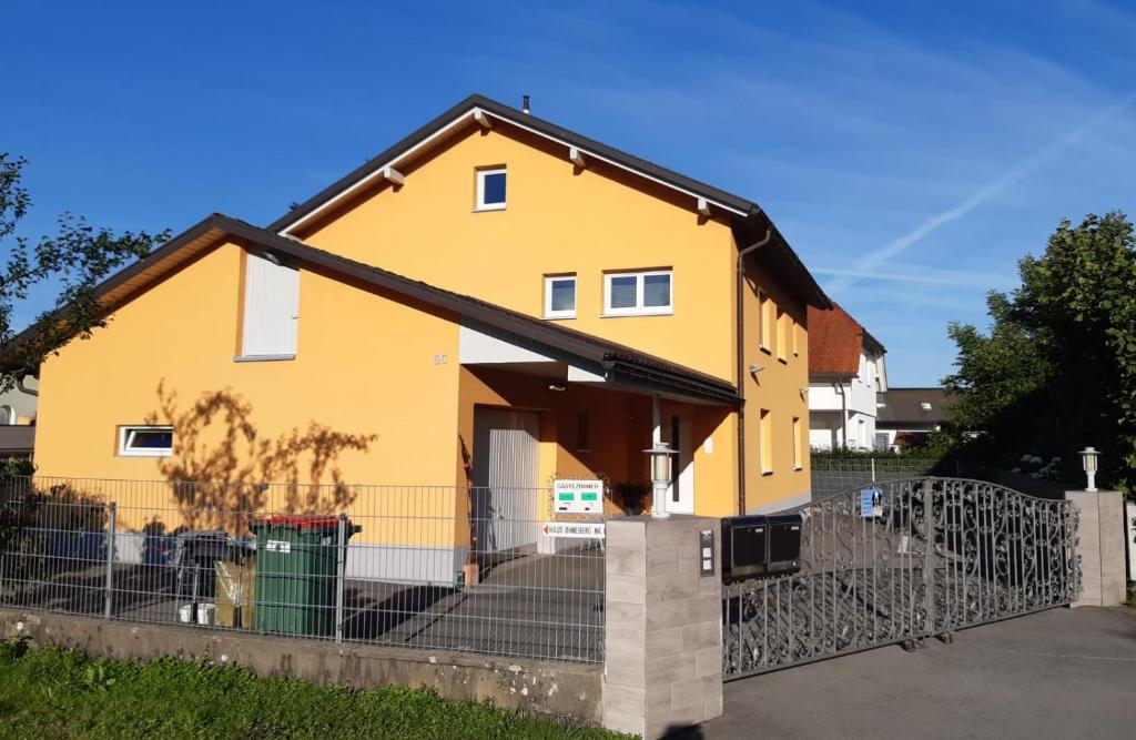 una casa amarilla con una valla delante de ella en Familie Ohneberg, en Hard