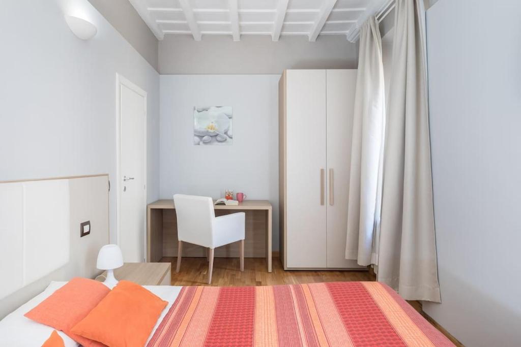 a bedroom with a bed with orange pillows and a desk at Spanish Steps House Vittoria in Rome