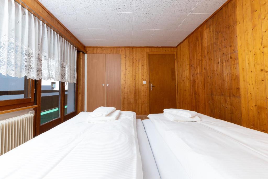 two white beds in a room with a window at Haus Slalom in Saas-Fee