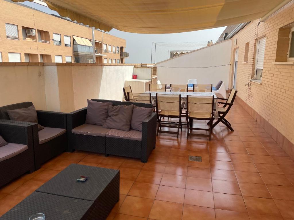 a balcony with a couch and a table and chairs at Impresionante ático duplex con 65m. De terraza con barbacoa para 10 personas in Picassent