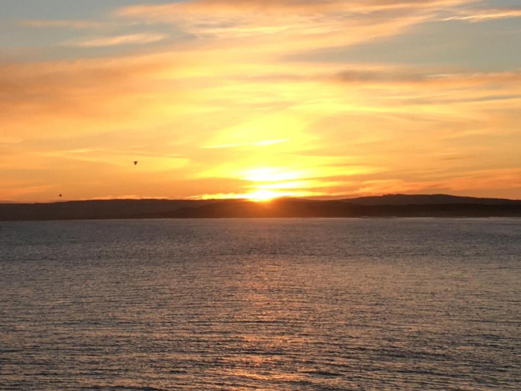 um pôr-do-sol sobre uma grande massa de água em Beachfront Panoramic Seaview Free Wifi & Parking em Lossiemouth