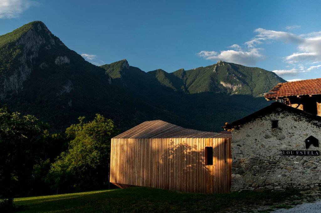 un edificio de madera con montañas en el fondo en Lou Estela - L'essiccatoio, en Moiola