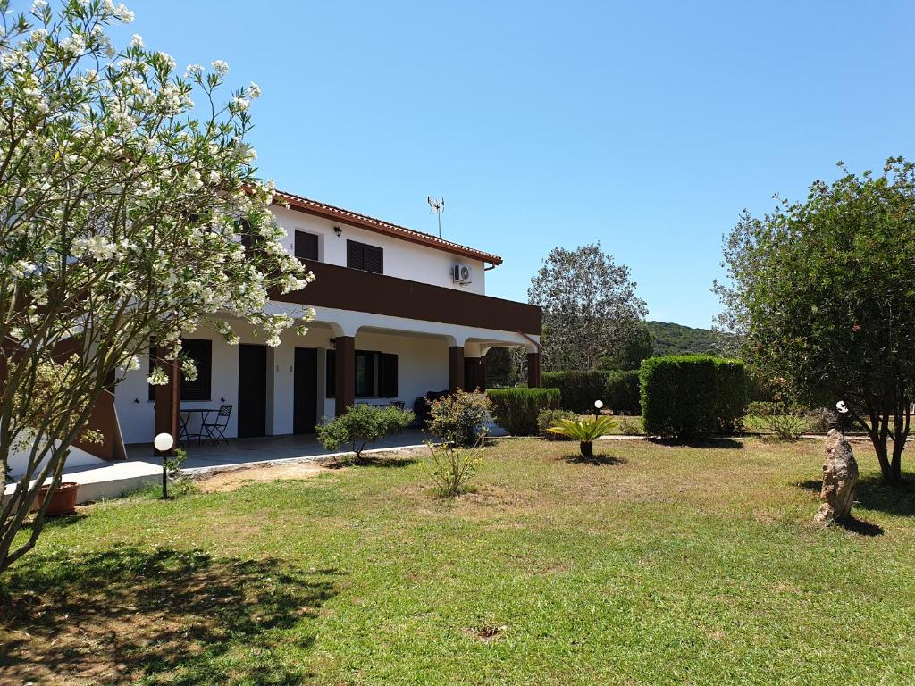 
a large white house with a tree in the front yard at Agriturismo Baratz in Santa Maria la Palma

