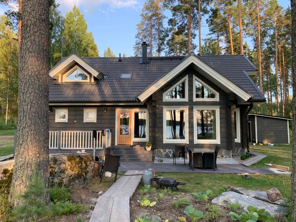 une maison en rondins avec une terrasse couverte et une maison dans l&#39;établissement Saimaan Villa Mustikka, à Äitsaari