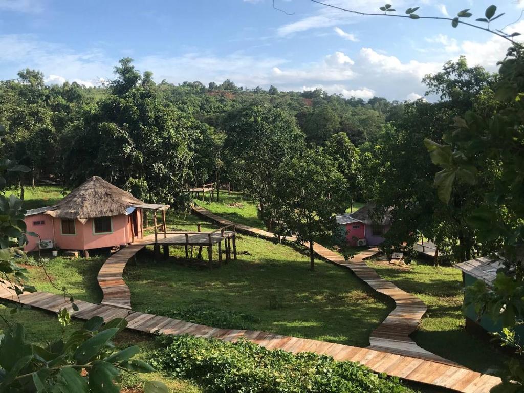 uma passagem que leva a uma pequena casa num campo em Gibbon Lodge em Sen Monorom