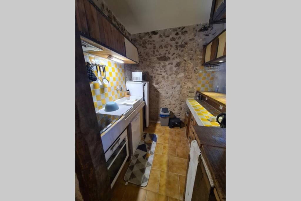 a small kitchen with a stove and a refrigerator at MAISON RESTAUREE 6 PERSONNES AU COEUR DU PERIGORD in Sourzac