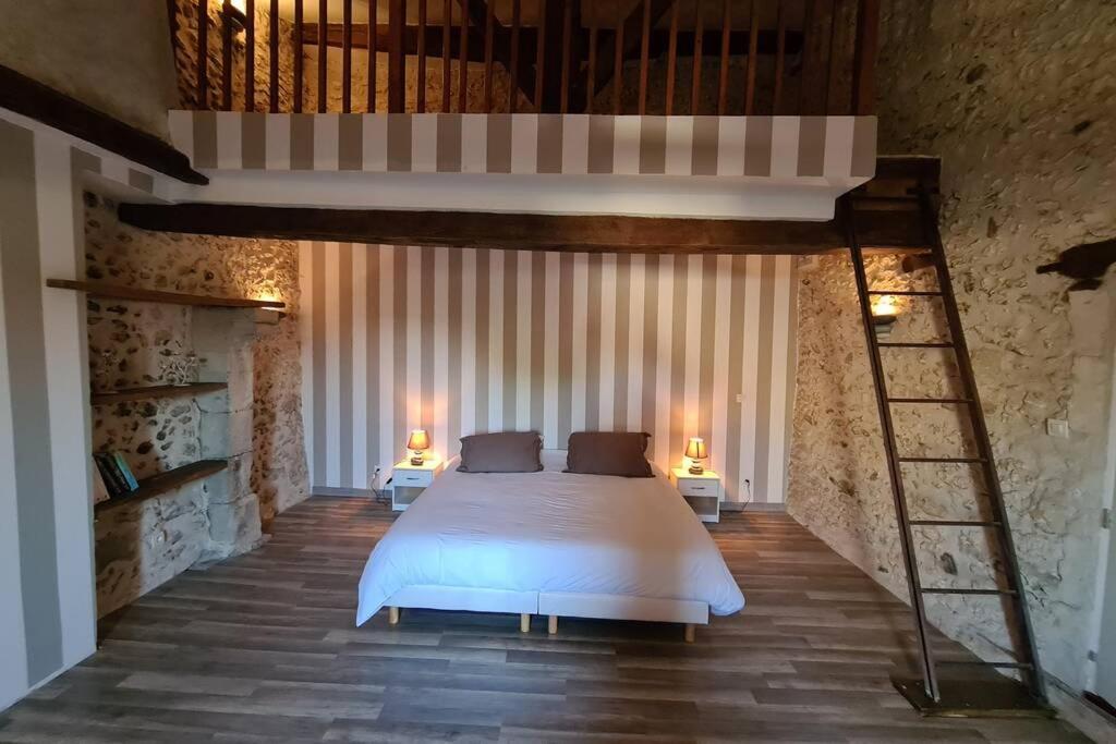a bedroom with a large white bed and a ladder at MAISON RESTAUREE 6 PERSONNES AU COEUR DU PERIGORD in Sourzac