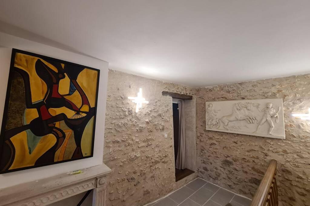 a room with paintings on the wall and a staircase at MAISON RESTAUREE 6 PERSONNES AU COEUR DU PERIGORD in Sourzac