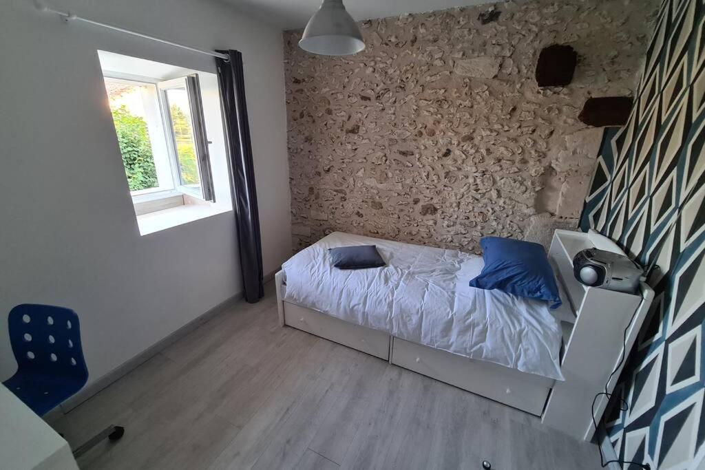 a small bedroom with a bed and a stone wall at MAISON RESTAUREE 6 PERSONNES AU COEUR DU PERIGORD in Sourzac