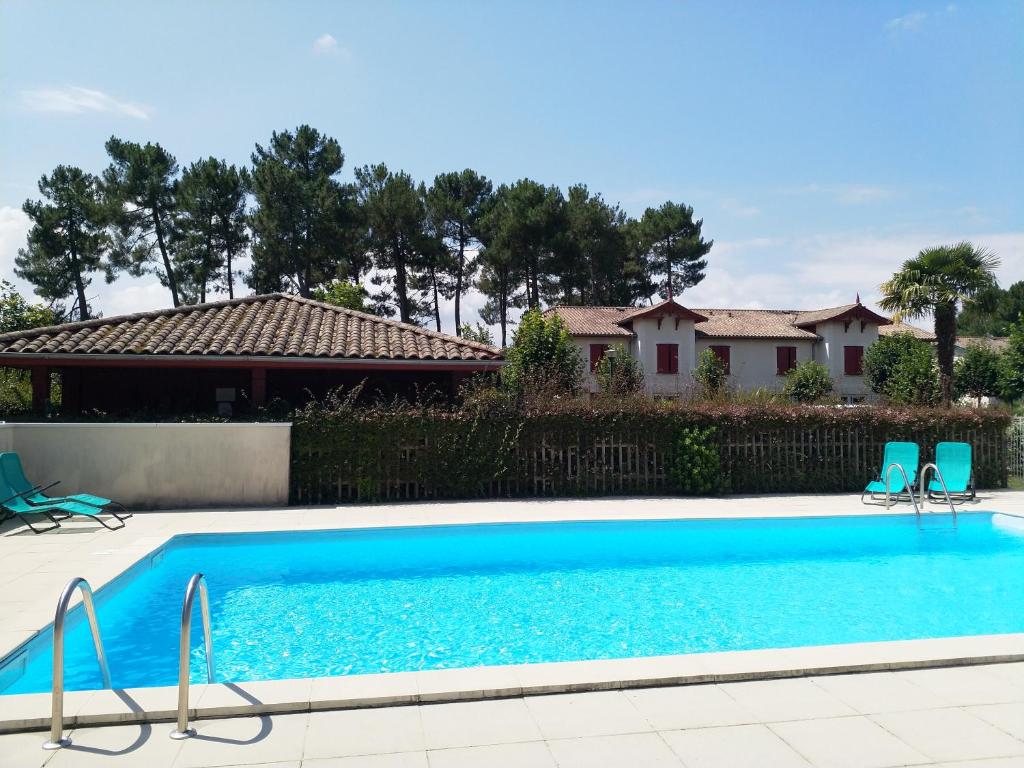 uma piscina com duas cadeiras e uma casa em Domaine des Pins Audenge Bassin d'Arcachon em Audenge