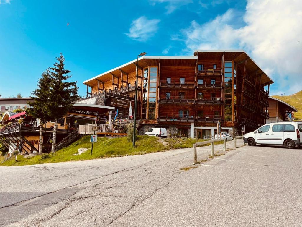 a large building with a car parked in front of it at Les Balcons De Recoin - Chamrousse in Chamrousse