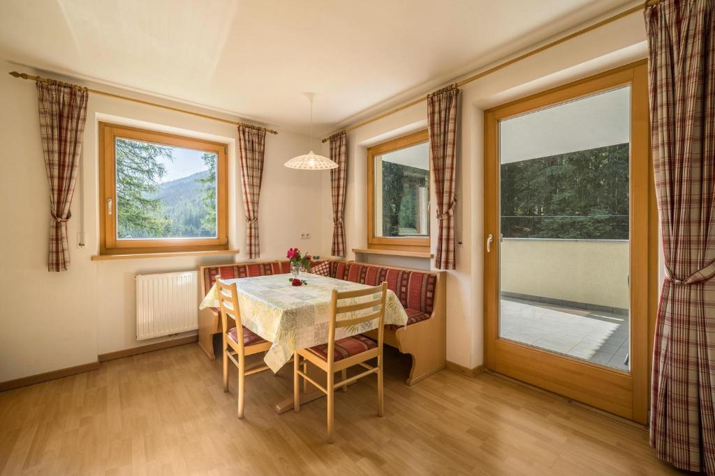comedor con mesa, sillas y ventanas en Ferienhaus Maria Schneeglöcklein, en Pfelders