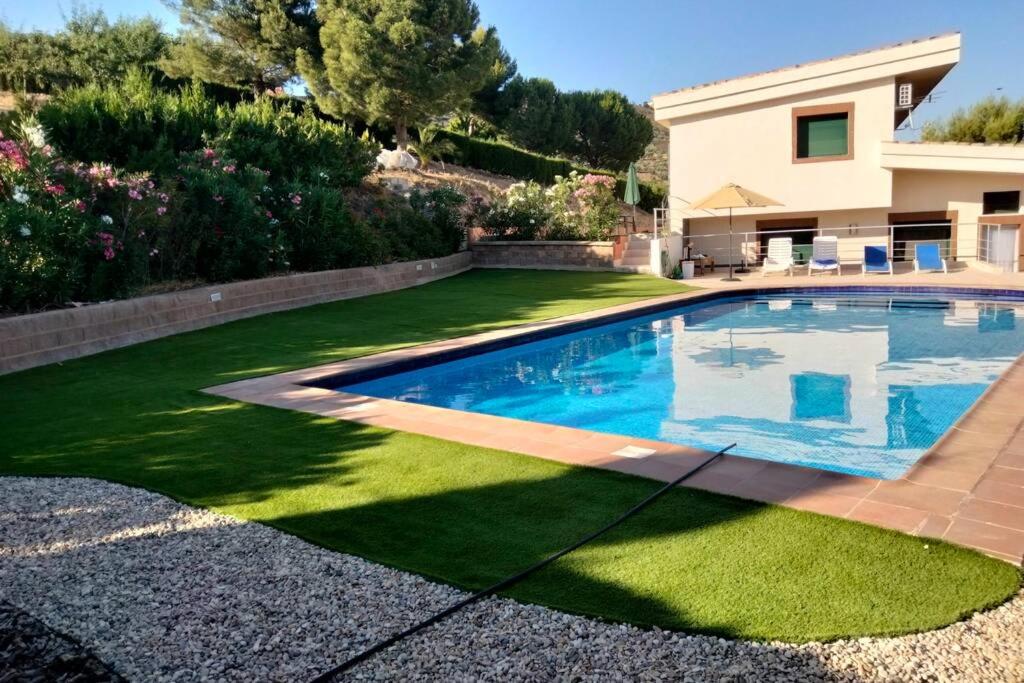 una piscina en un patio con césped verde en Alojamiento Rural La Viña del Cerezo, en Huelma