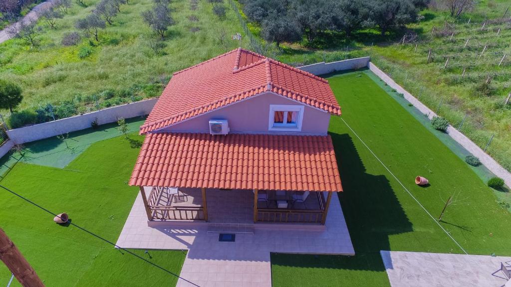 a small house with an orange roof on a green field at Villa ARETOUSA - Cretan Hospitality in Protória