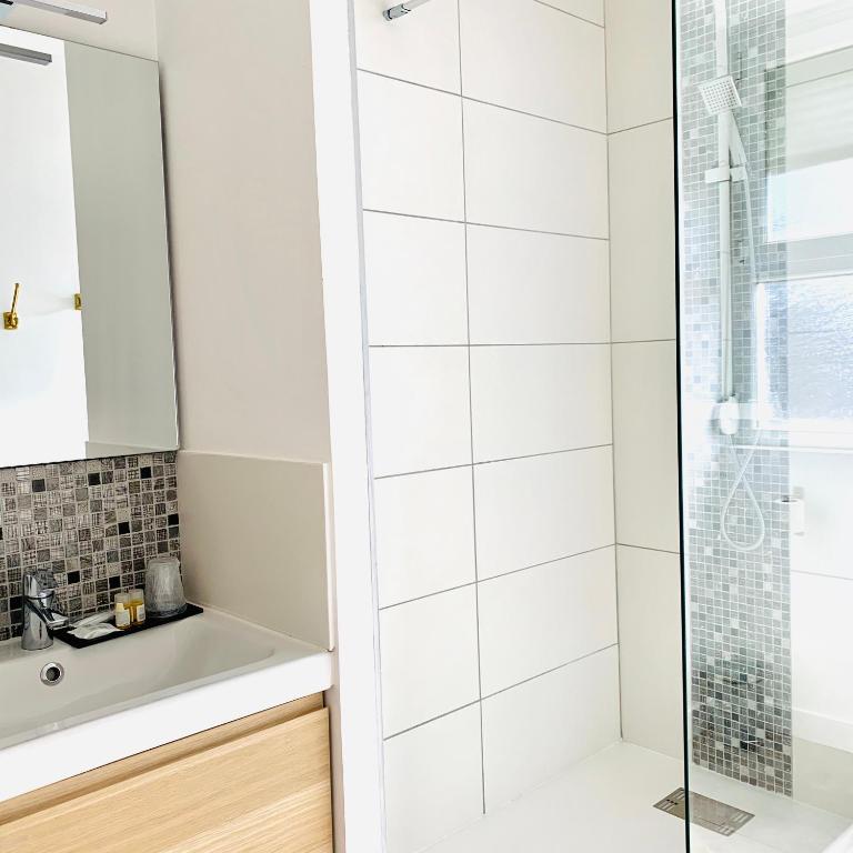 a white bathroom with a shower and a sink at Hôtel Jules in Le Touquet-Paris-Plage