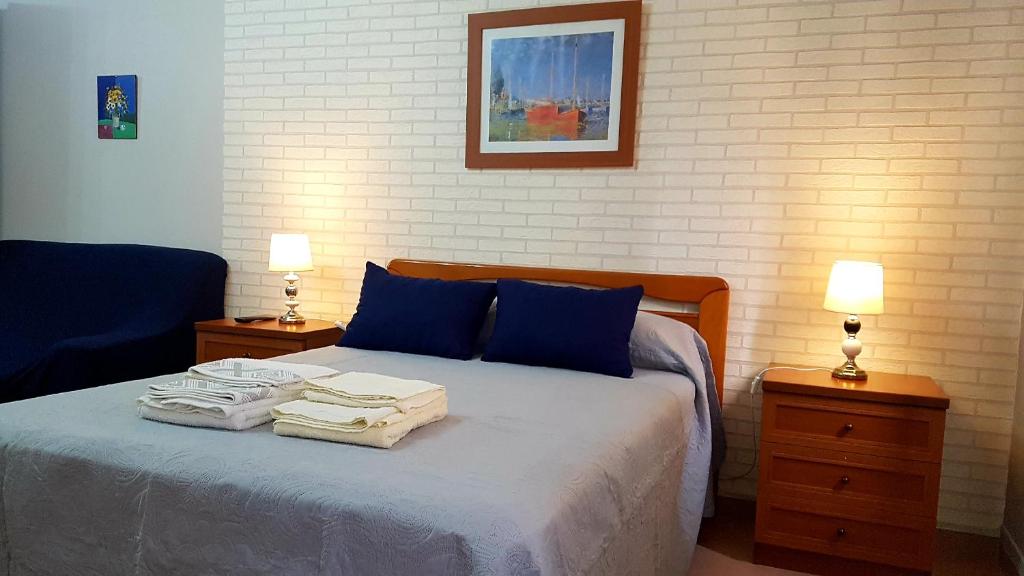 a bedroom with a bed with blue pillows and two lamps at Apartamento Loft II Select Real Caldas de Reis in Caldas de Reis