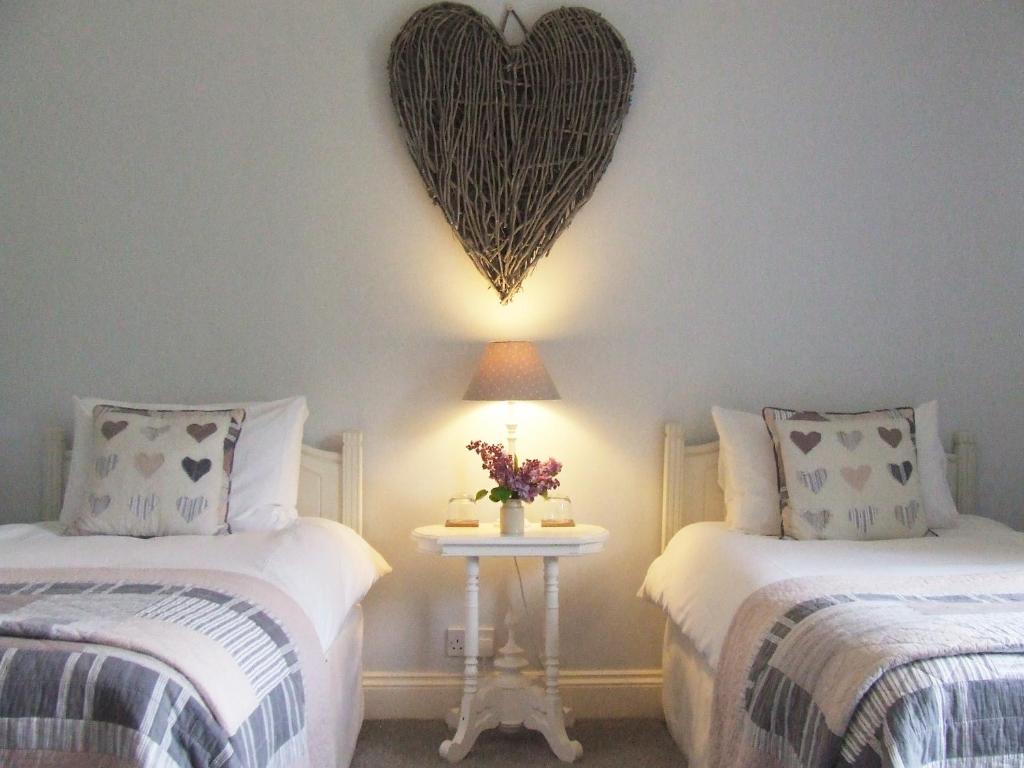 a bedroom with two beds with a heart on the wall at Lobhill Farmhouse Bed and Breakfast and Self Catering Accommodation in Okehampton