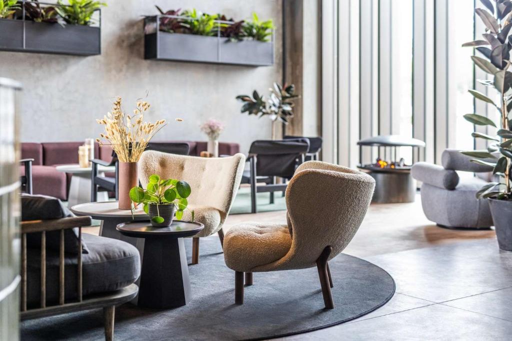 un hall avec des chaises, des tables et des plantes en pot dans l'établissement Peak 12 Hotel, à Viborg