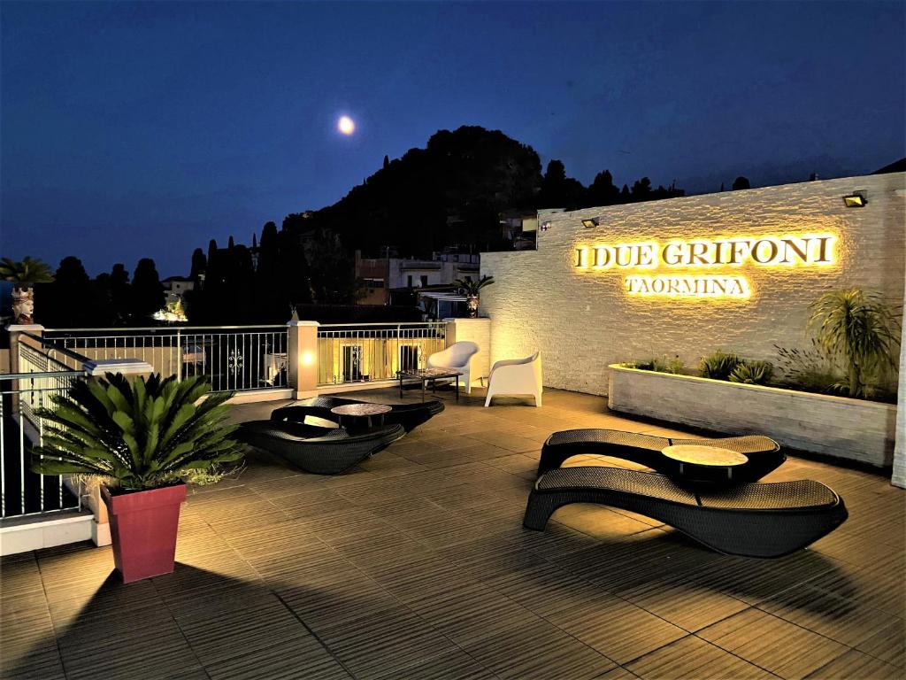 a deck with chairs and a sign on a building at I Due Grifoni Apartments in Taormina