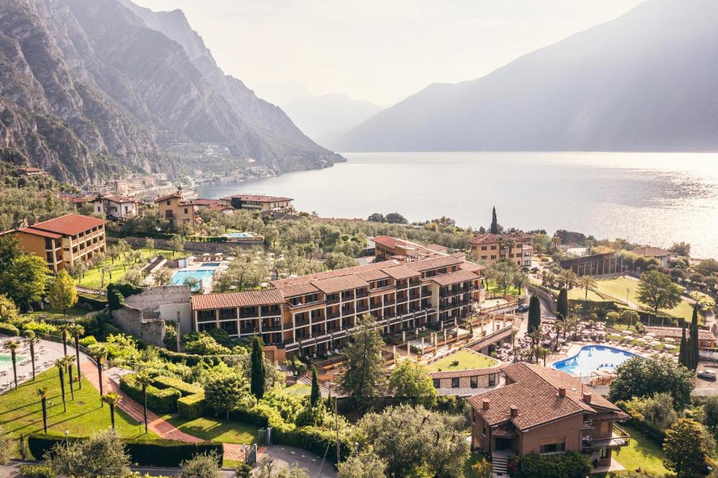 um resort com um lago e montanhas ao fundo em Hotel Caravel em Limone sul Garda