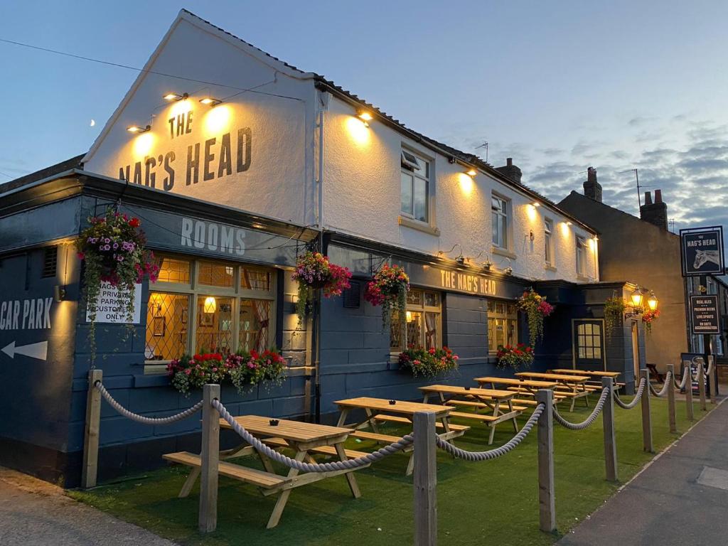 un grupo de mesas de madera frente a un edificio en The Nags Head York, en York