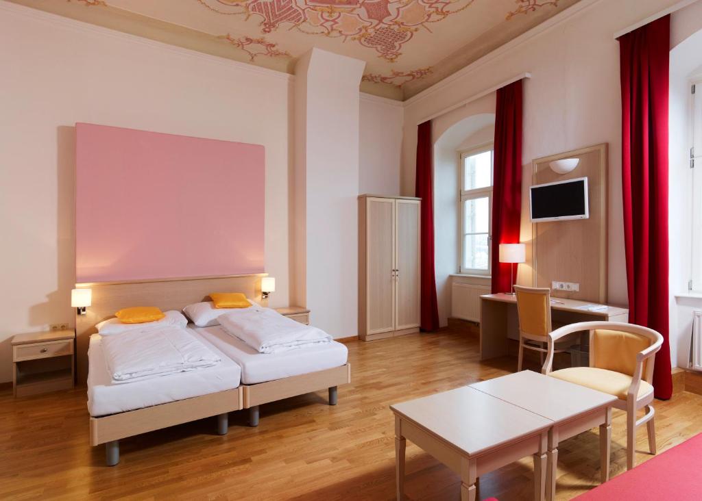 Habitación de hotel con 2 camas y mesa en CMA Stift Ossiach en Ossiach