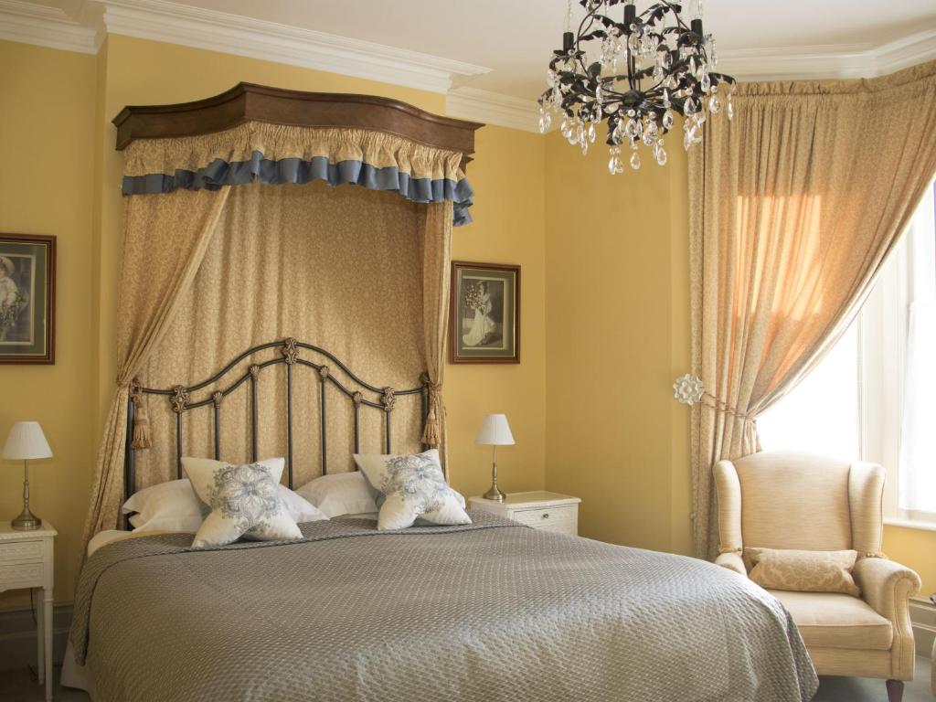 a bedroom with a large bed and a chandelier at Albert & Victoria Guest House in Eastbourne