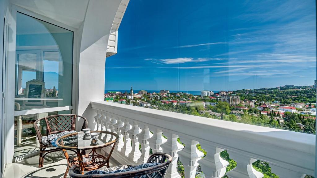 a balcony with two chairs and a view of the city at Villa Bonne Maison in Alushta