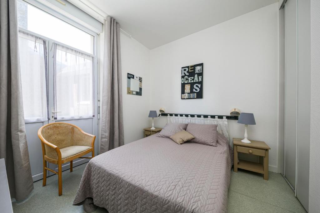 1 dormitorio con 1 cama, 1 silla y 1 ventana en Résidence du Prieuré, en Dinard