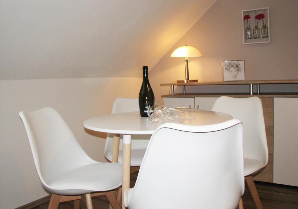 einen Tisch mit weißen Stühlen und eine Flasche Wein in der Unterkunft FEWO Schinkestrasse in Bad Schandau