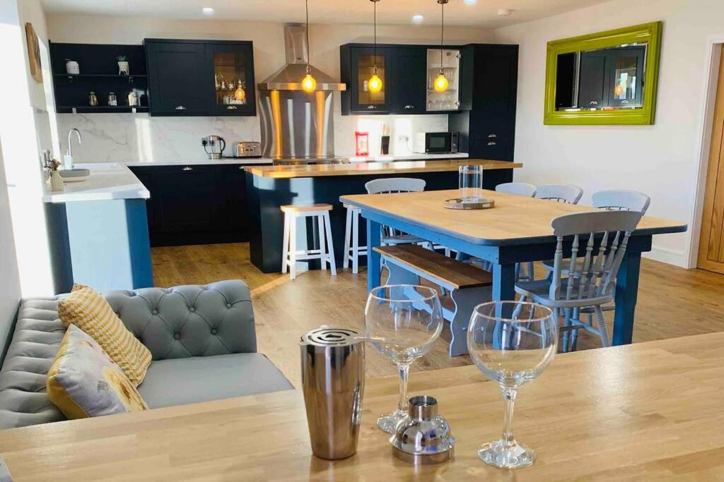 a kitchen and living room with a table and wine glasses at Nether Newton - Sleeps 10, Hottub, Sauna, Private Garden in Newmilns