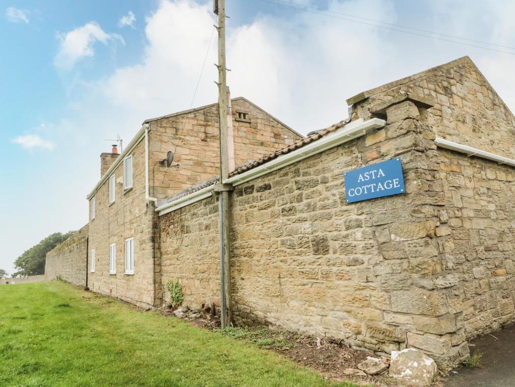 an old brick building with a blue sign on it at Asta Cottage in Morpeth