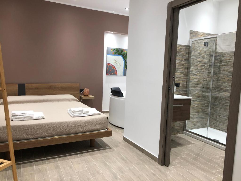 1 dormitorio con 1 cama y puerta de cristal al baño en Dimore Albrunè en Catania