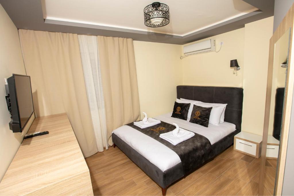 Hotel Sonoma في Kosovo Polje: غرفة نوم بسرير وتلفزيون بشاشة مسطحة