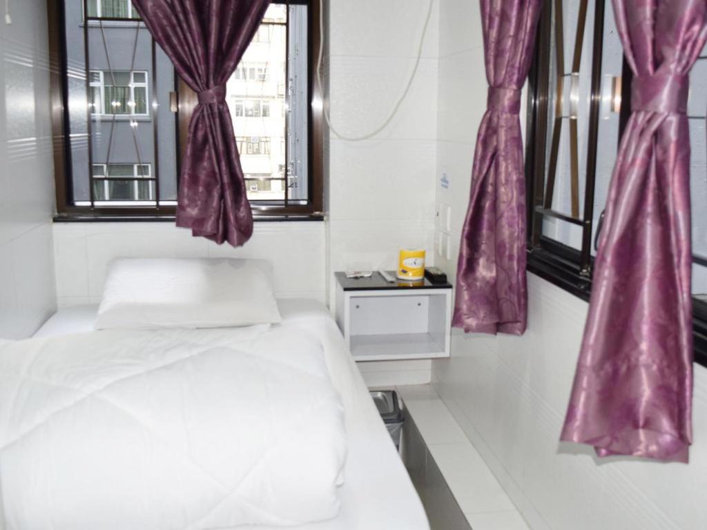 Schlafzimmer mit violetten Vorhängen, einem Bett und Fenstern in der Unterkunft Strawberry Guest house in Hongkong