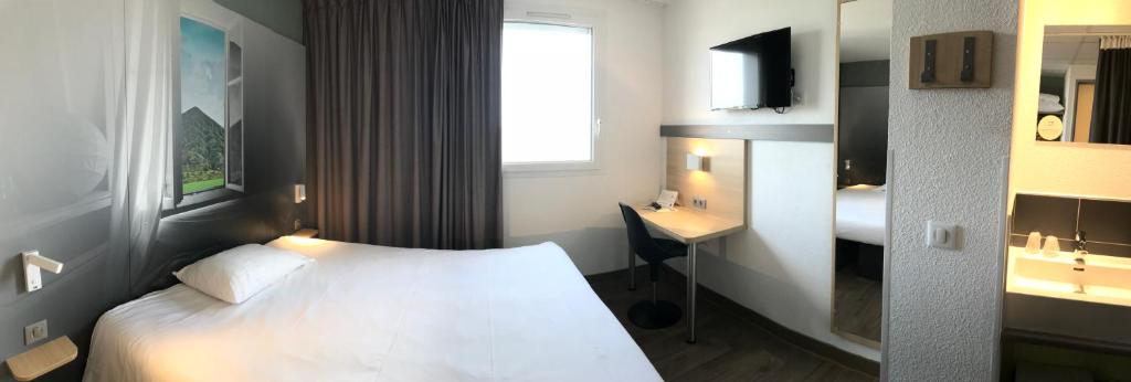 a hotel room with a white bed and a desk at B&B HOTEL Béthune Bruay-la-Buissière in Bruay-la-Buissiere