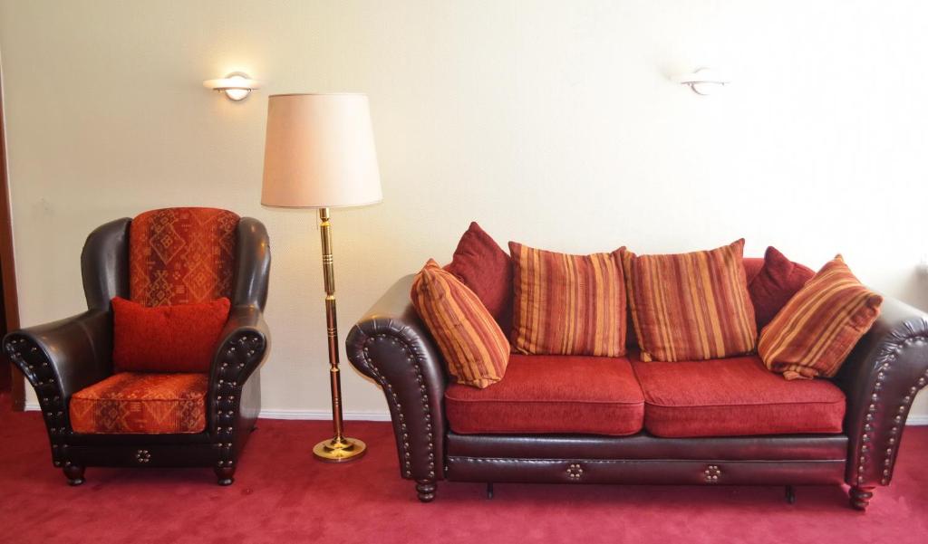 ein Wohnzimmer mit einem roten Sofa und einem Stuhl in der Unterkunft Kurfürst am Kurfürstendamm in Berlin